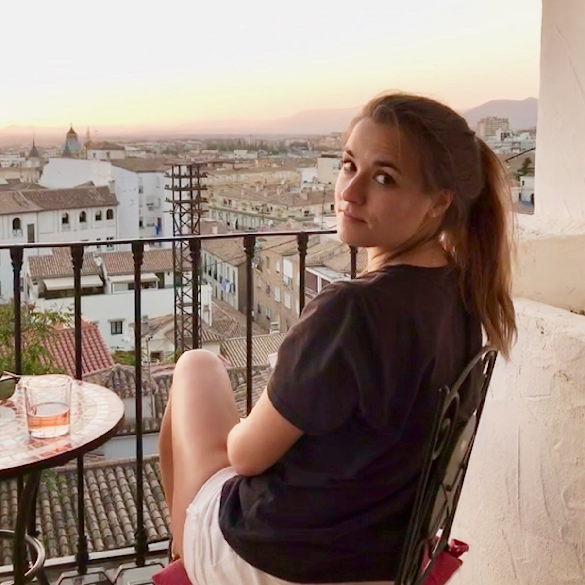 Mary Katherine in Granada with the sun setting in the background and a glass of rose on the table.